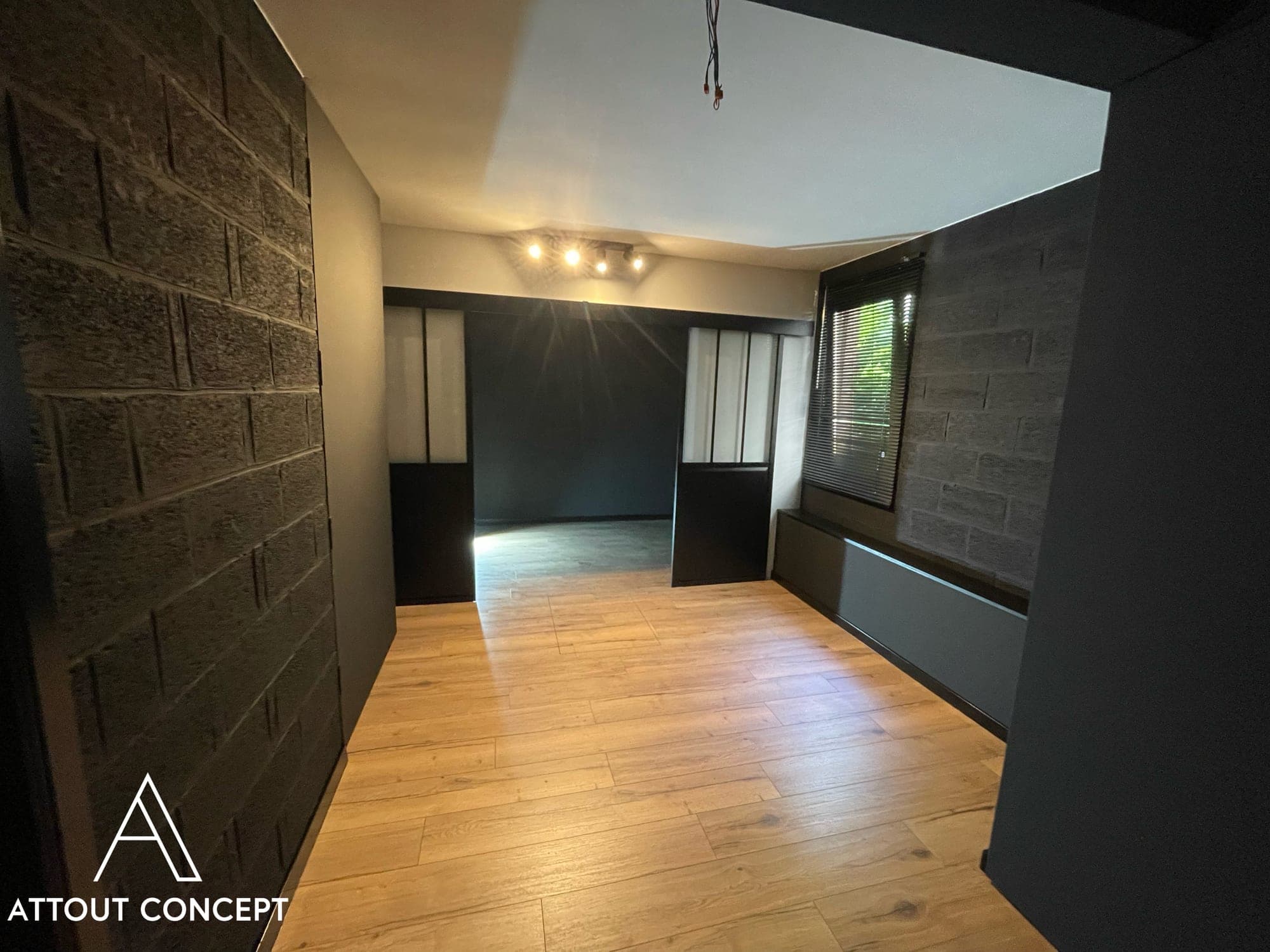 Pièce réaménagée aux murs noirs, portes coulissantes et parquet clair