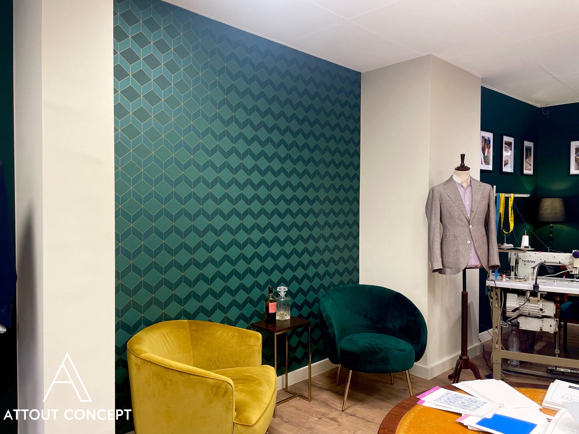 Papier peint géométrique vert émeraude et fauteuils en velours dans une boutique de tailleur
